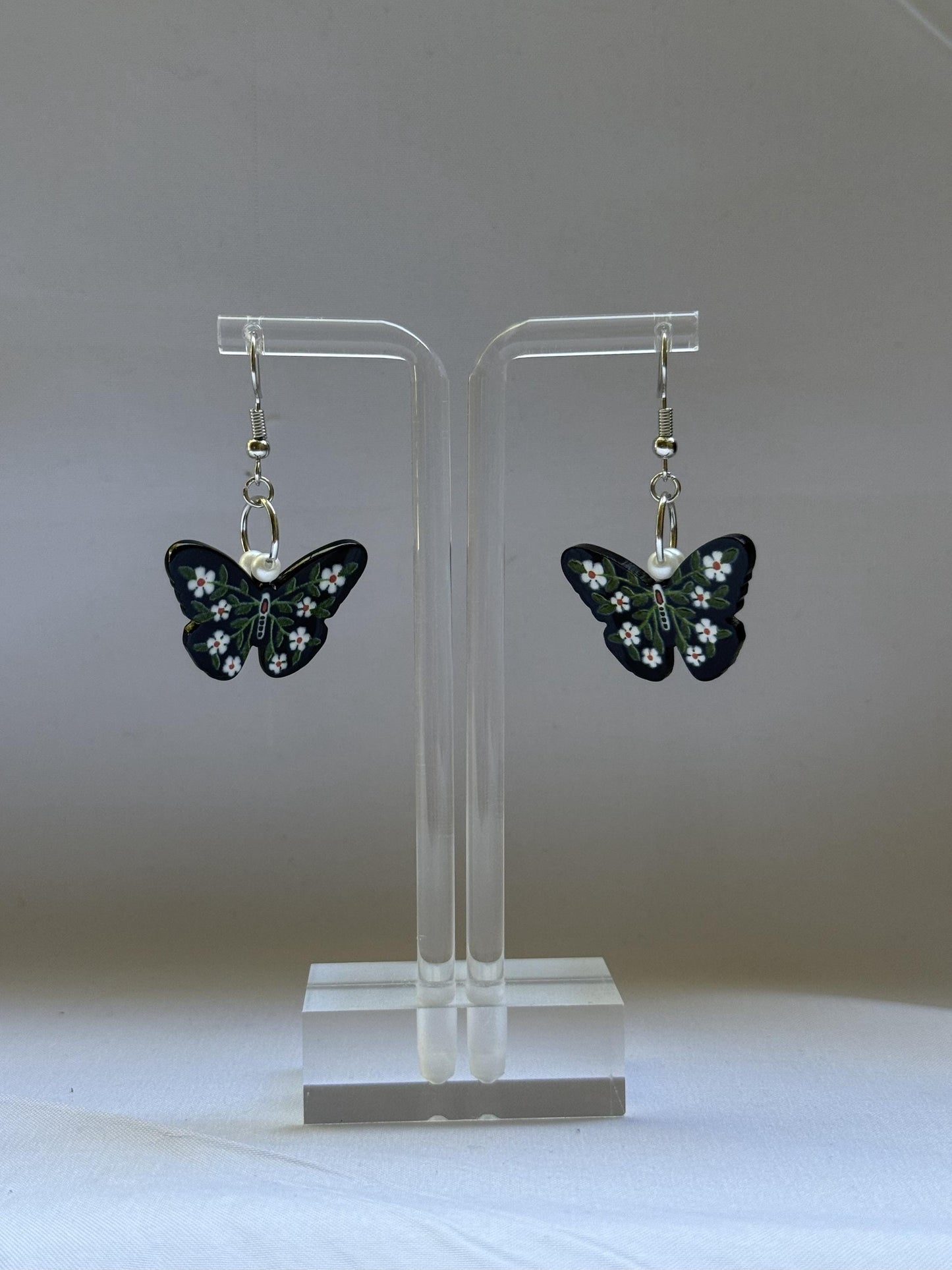 Butterfly earrings on a clear stand against a white background