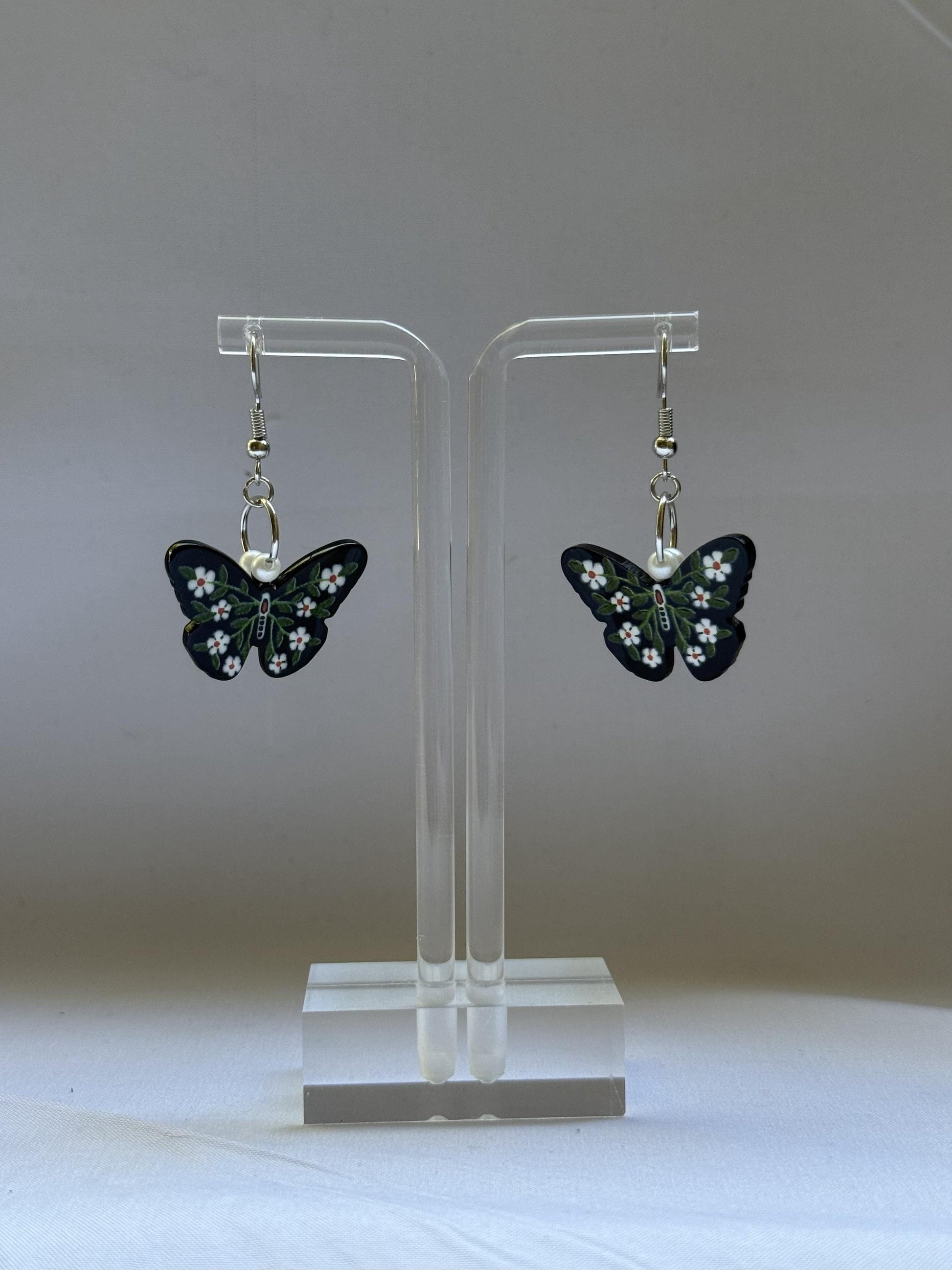 Butterfly earrings on a clear stand against a white background
