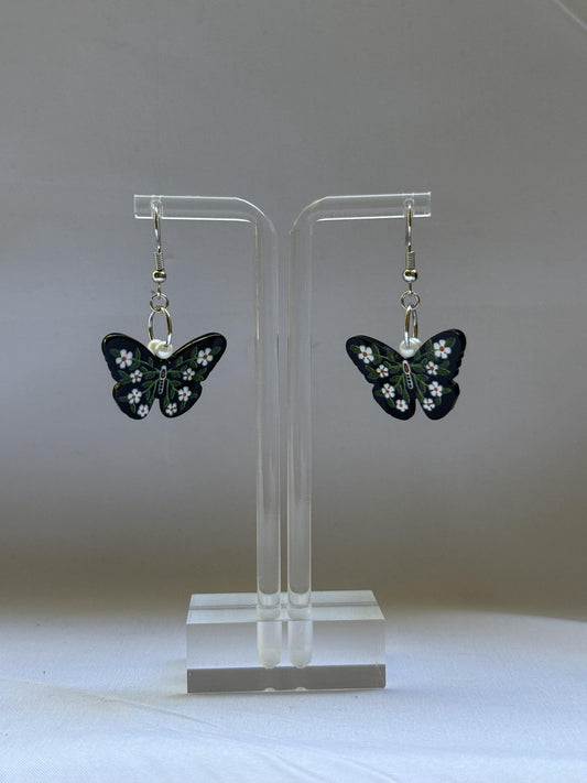 Butterfly earrings on a clear stand against a white background